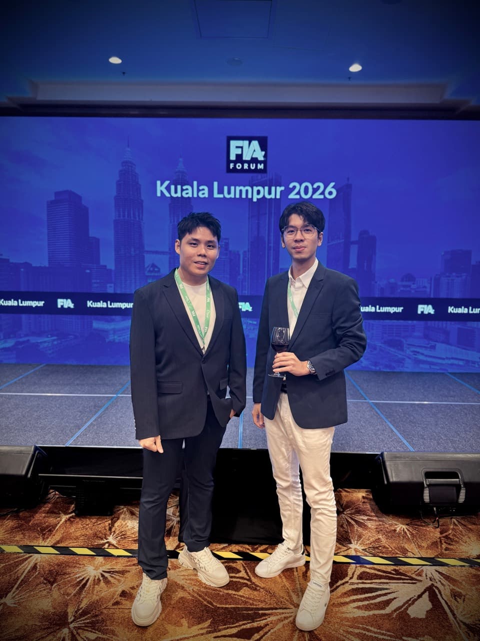 Two attendees in front of the FIA Forum Kuala Lumpur 2026 stage